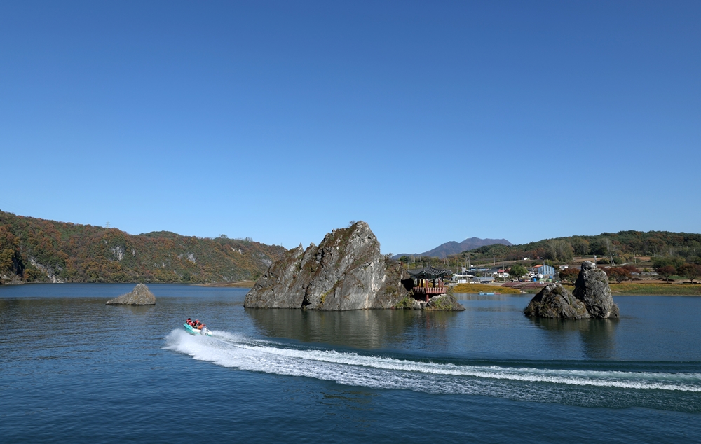 A boat carrying the group on Nov. 6 speeds across the Dodamsangdong Peaks in Danyang-gun County, Chungcheongbuk-do Province.